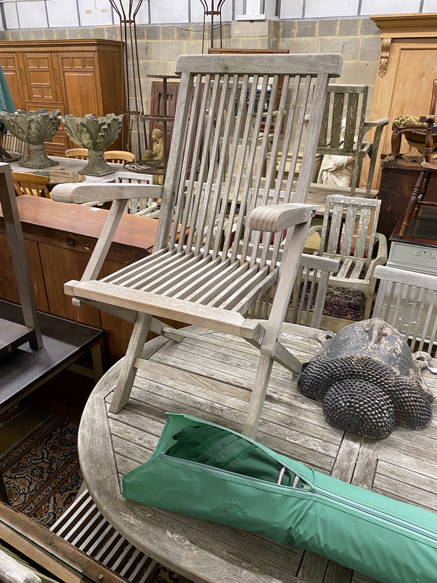 A Lindsey teak garden table with eight chairs and a parasol